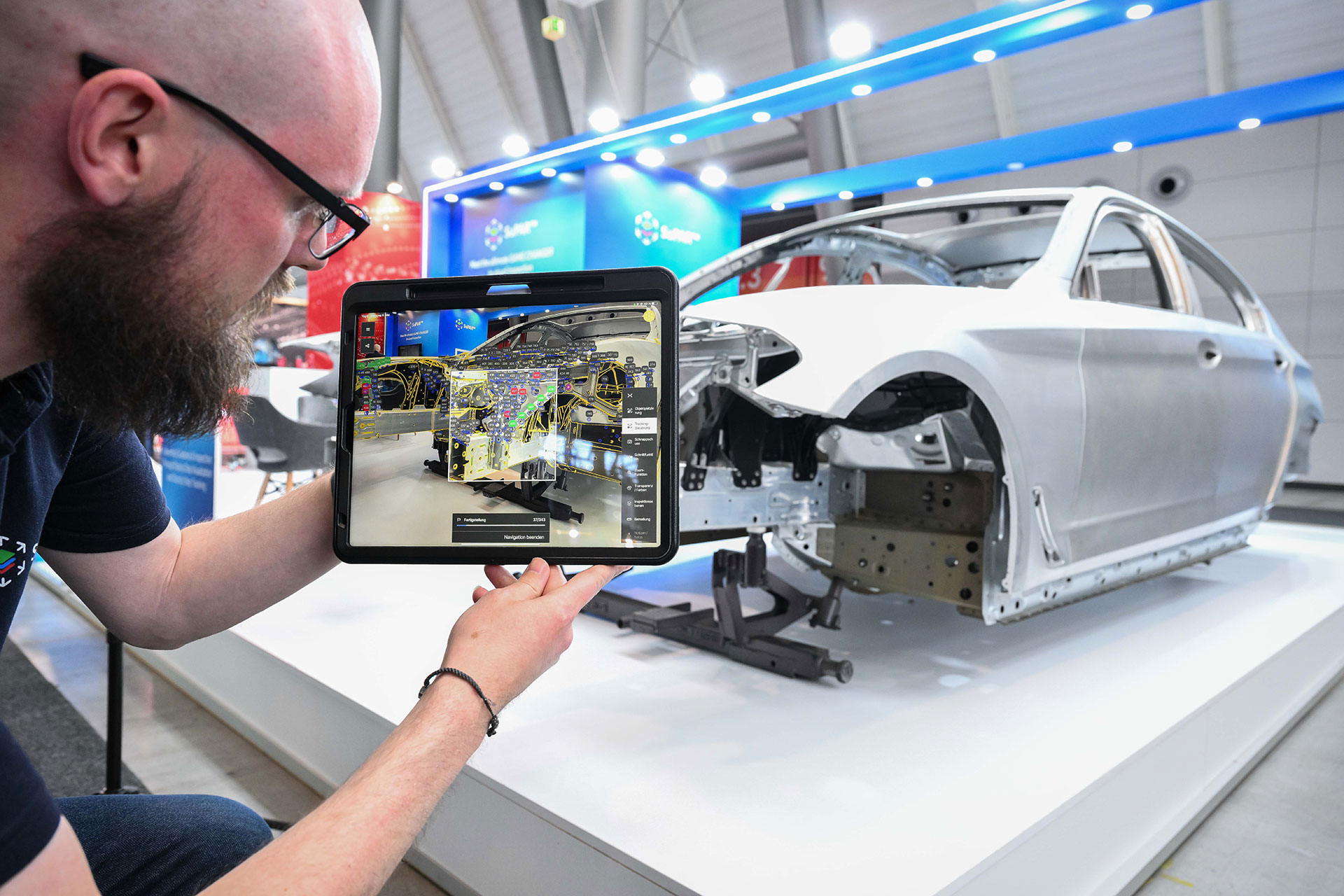 Prüfer vergleicht per Tablet das CAD‑Modell mit einer realen Fahrzeugkarosserie